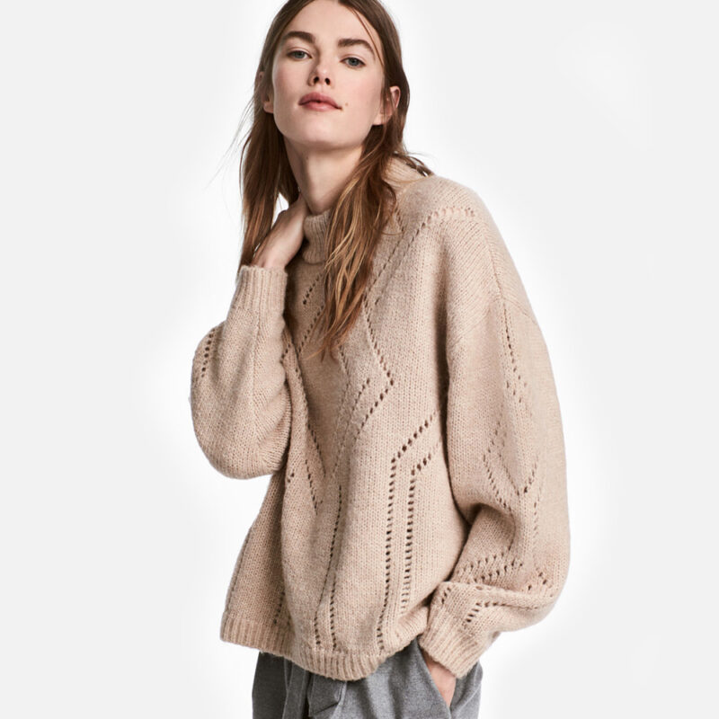 Woman wearing a cozy beige cable-knit sweater.