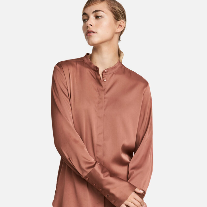 Woman wearing a silky brown blouse with long sleeves.