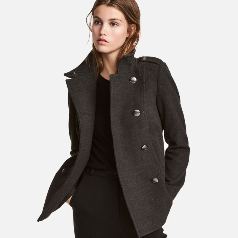 Woman wearing a stylish black coat with buttons.