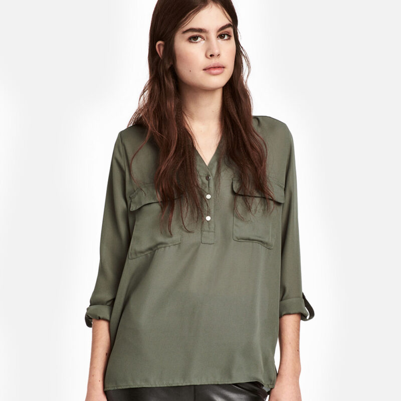 Young woman wearing an olive green long-sleeve blouse.