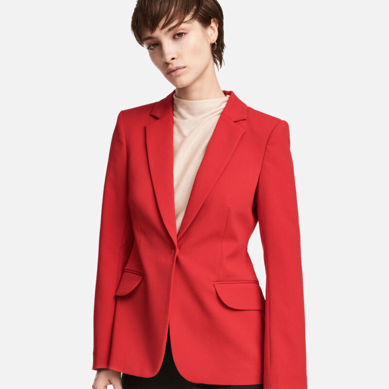 Woman wearing a stylish red blazer and beige turtleneck.